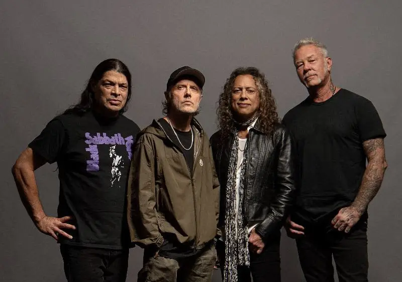 The four members of Metallica standing together in a studio portrait against a grey backdrop